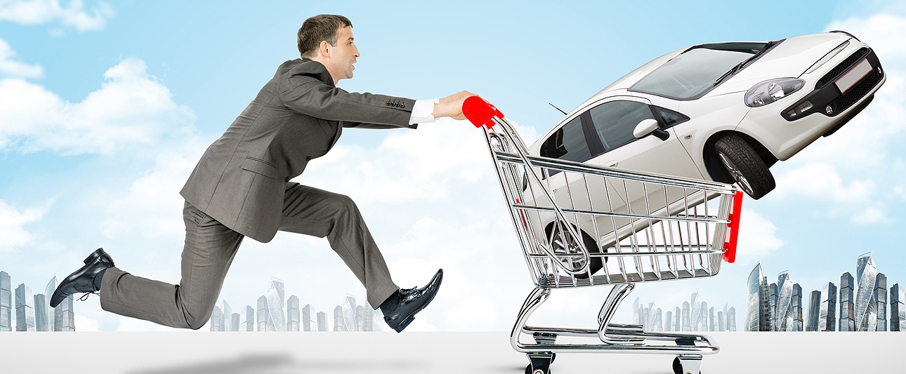 Mann im Anzug der einen PKW im Einkaufswagen schiebt, im Hintergrund die Silhouette einer Großstadt